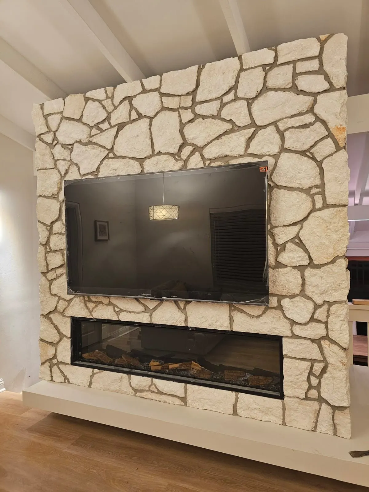 Full-height sandstone crazy cladding around a fireplace and television