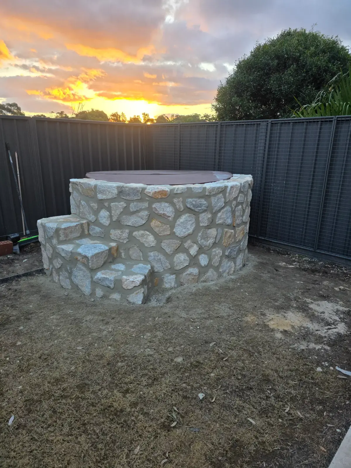 Hand-dressed natural stone cladding on a circular outdoor feature wall at sunset